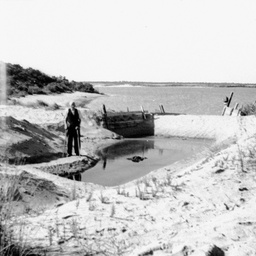 A man standing by a mooring basin or fishing dam at The Coorong