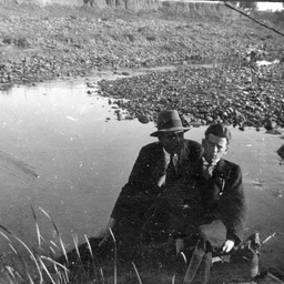 Two men sitting beside a waterhole