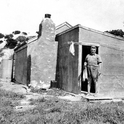 Man holding his fish catch at the doorway of a shack on The Coorong