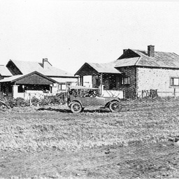 Early view of Barmera with car parked in front of houses and dirt road